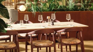 A dining area with a table set for four, surrounded by chairs, in a room with indoor plants and a modern interior design. - Novotel Zagreb - opened September 2025 (Zagreb)