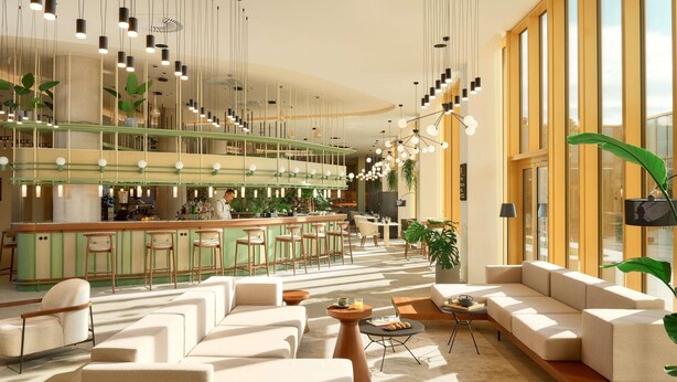 A modern bar area with a bar counter, seating, and hanging lights. - Novotel Zagreb - opened September 2025 (Zagreb)