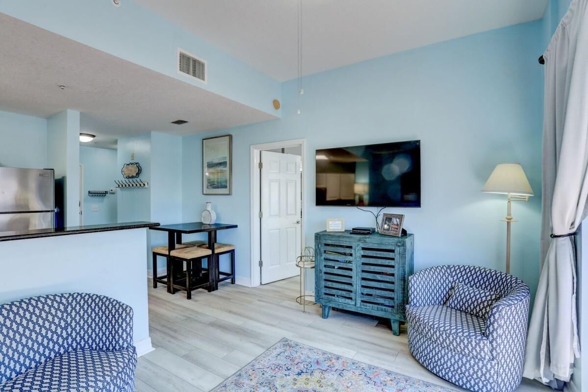 A living room with a blue sofa, a patterned sofa, a wooden coffee table, a TV, and a lamp.