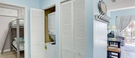 A room with a bunk bed, a washing machine, and a dining area with a table and chairs.