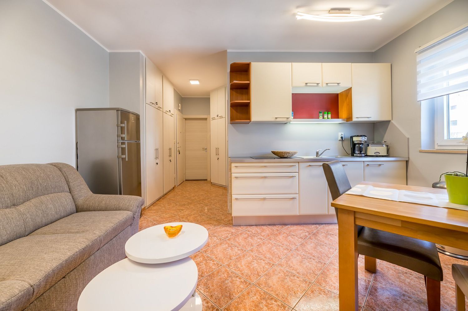 Een knus woongedeelte met een kitchenette, een eethoek en een bank.