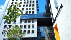 Een modern hoog gebouw met meerdere verdiepingen, grote ramen en een gevel van glas en beton.