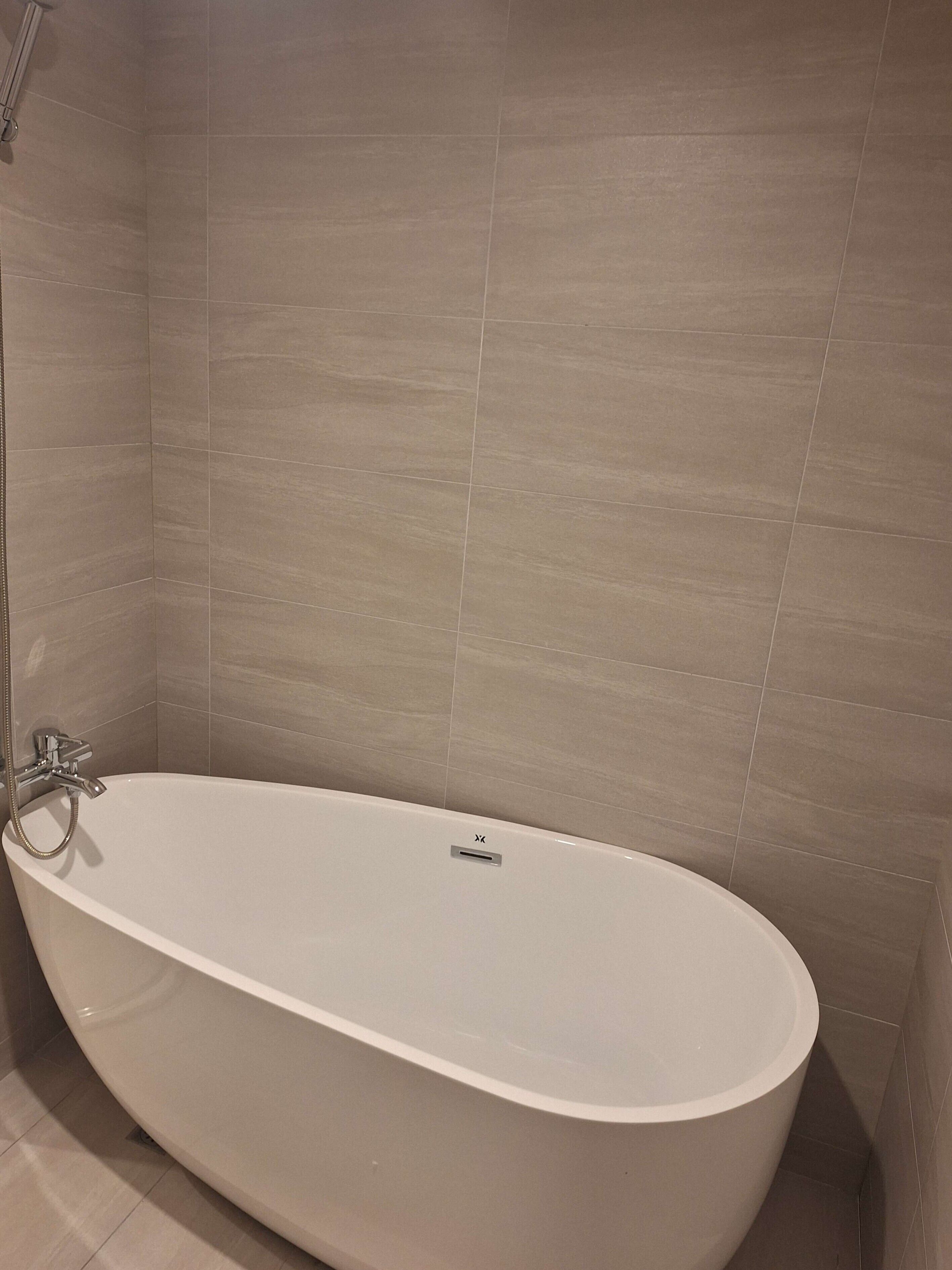 A modern bathroom with a freestanding bathtub, tiled walls, and a showerhead.