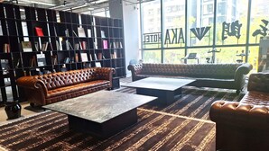 Een moderne lounge met leren banken, een marmeren salontafel en een boekenkast vol boeken.