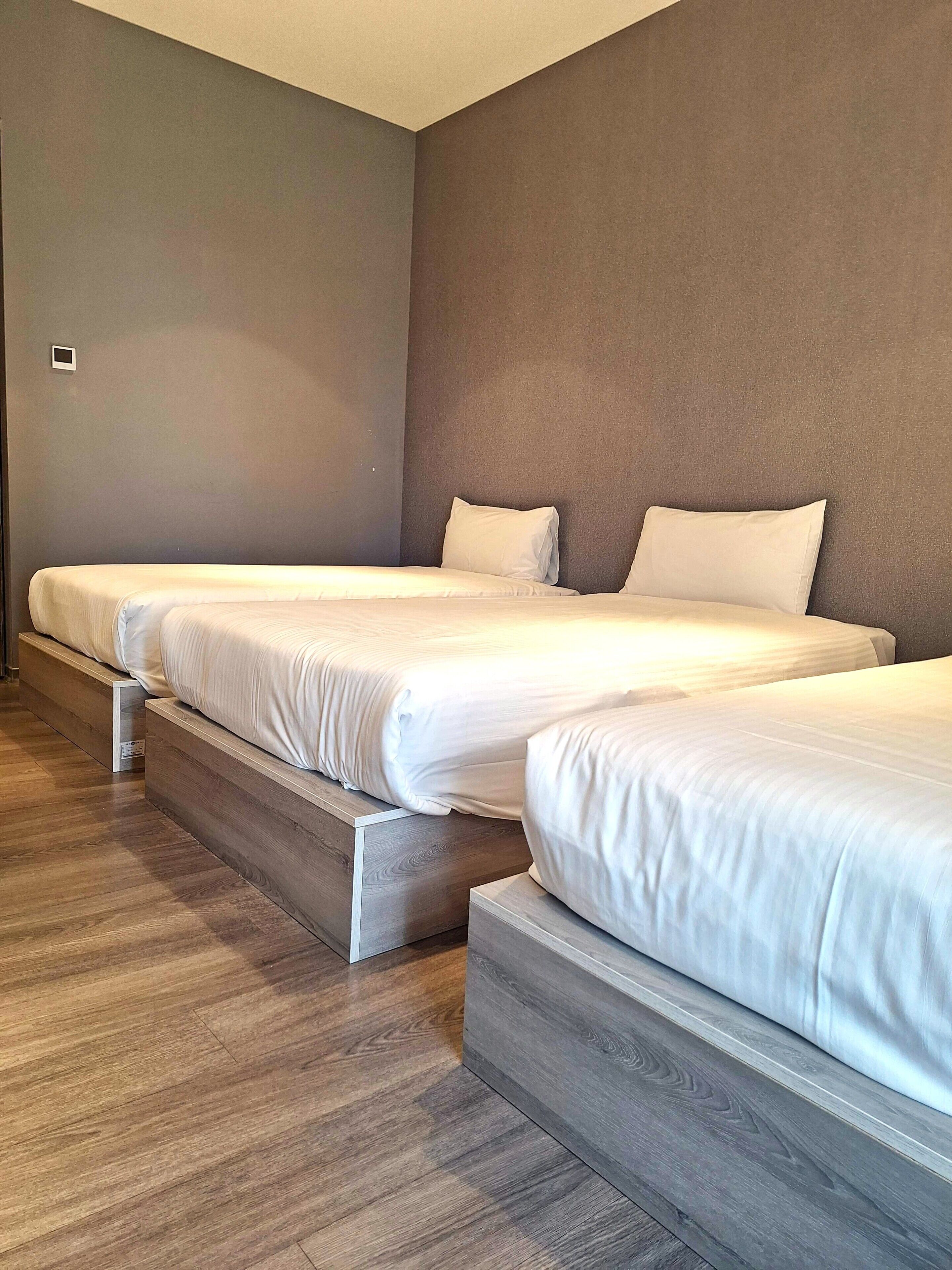 Habitación de hotel con dos camas, piso de madera y una paleta de colores neutros.