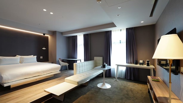 Een moderne hotelkamer met een groot bed, een bank, een eettafel en een bureau.
