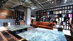 Een moderne hotellobby met marmeren tafels, een leren bank en een boekenkast vol boeken en tijdschriften.
