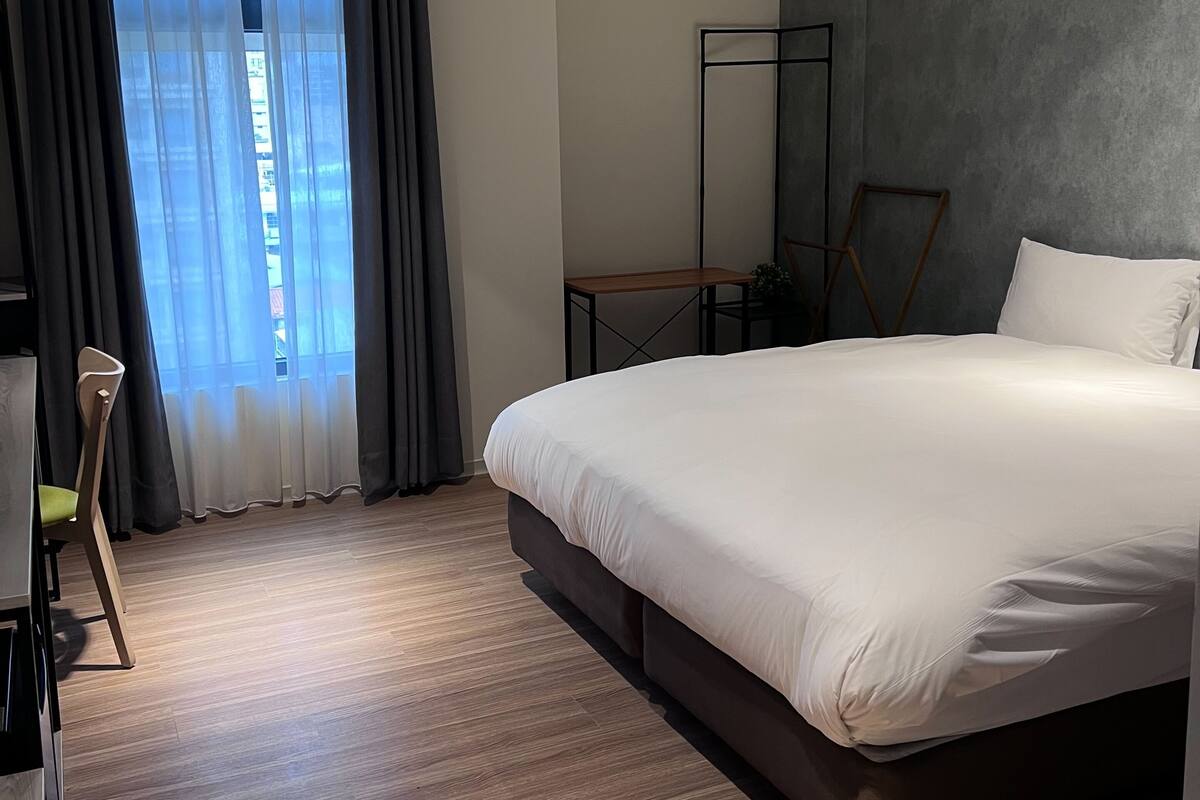 Una habitación de hotel moderna con una cama grande, un escritorio y una silla.