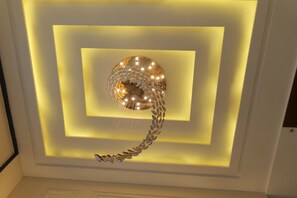 A modern ceiling with a central spherical light fixture surrounded by illuminated geometric shapes. - THE KEMBERLY HOTEL (Zirakpur)