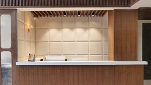 Un comptoir d’accueil avec un revêtement en bois, un plan de travail blanc et un mur recouvert de carreaux derrière.