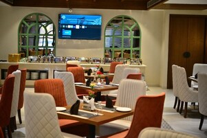 Un restaurante con mesas y sillas, una pantalla de televisión y ventanas de arco.