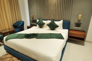 Una cama bien hecha con almohadas verdes, un cabecero azul y una mesita de noche con una lámpara.