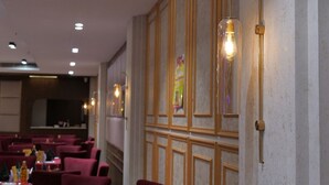 L’intérieur d’un restaurant, avec des tables et des chaises, des spots encastrés au plafond et des appliques murales.