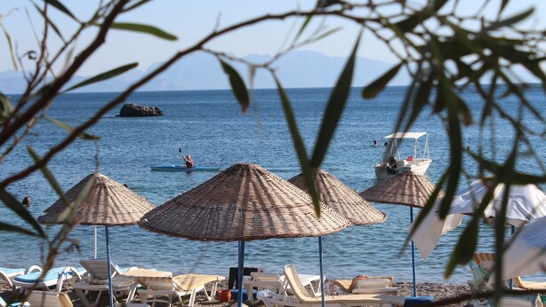 A beach with several sun umbrellas and lounge chairs. - Incekum Pansiyon (Maziköy)