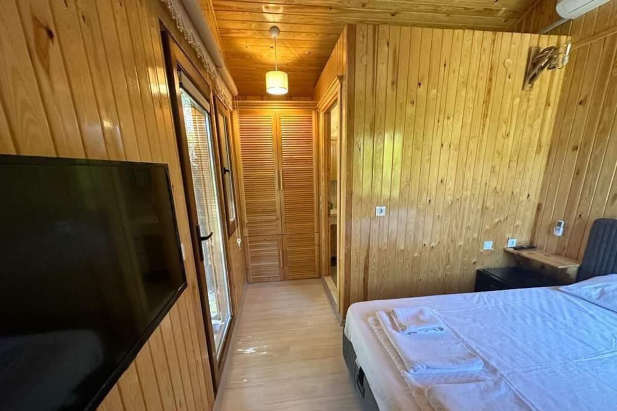 Habitació amb panells de fusta, un llit, una televisió i una porta corredissa que dóna a un passadís.