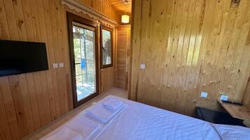 Una habitación de cabaña de madera con una cama, una ventana y una pequeña mesa.