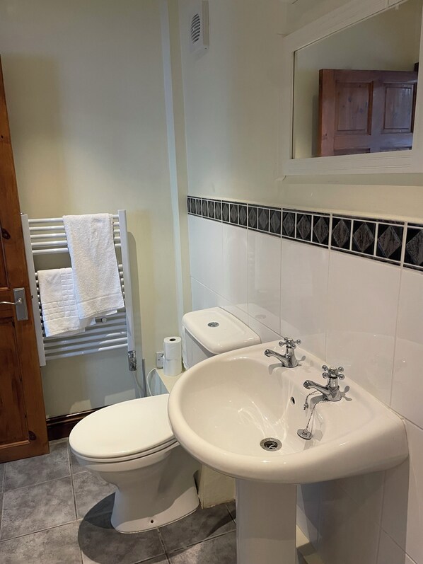 A bathroom with a toilet, a sink, and a towel rack. - Rooms at the Huntsman Inn (Falfield)