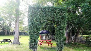 A picnic area with a table and benches, surrounded by lush greenery and trees. - Rooms at the Huntsman Inn (Falfield)