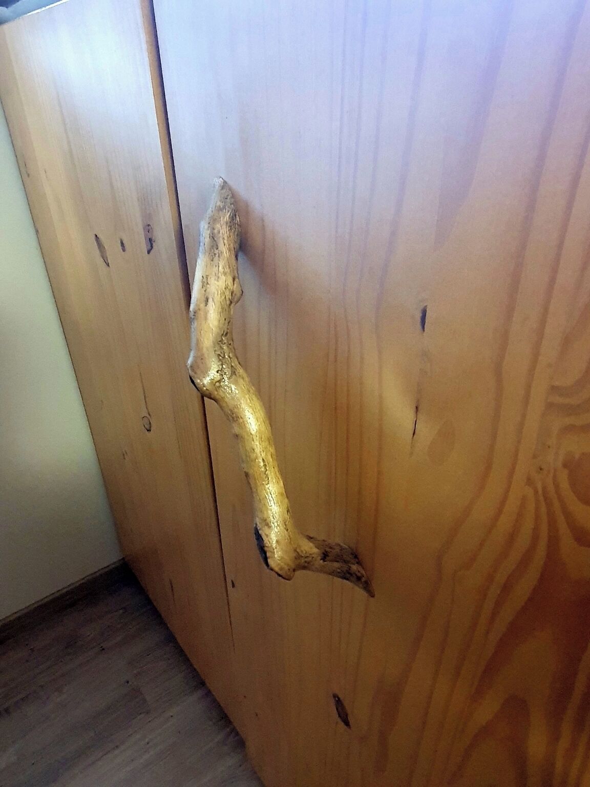 Eine Holztür mit einem natürlichen, unregelmäßig geformten Griff.