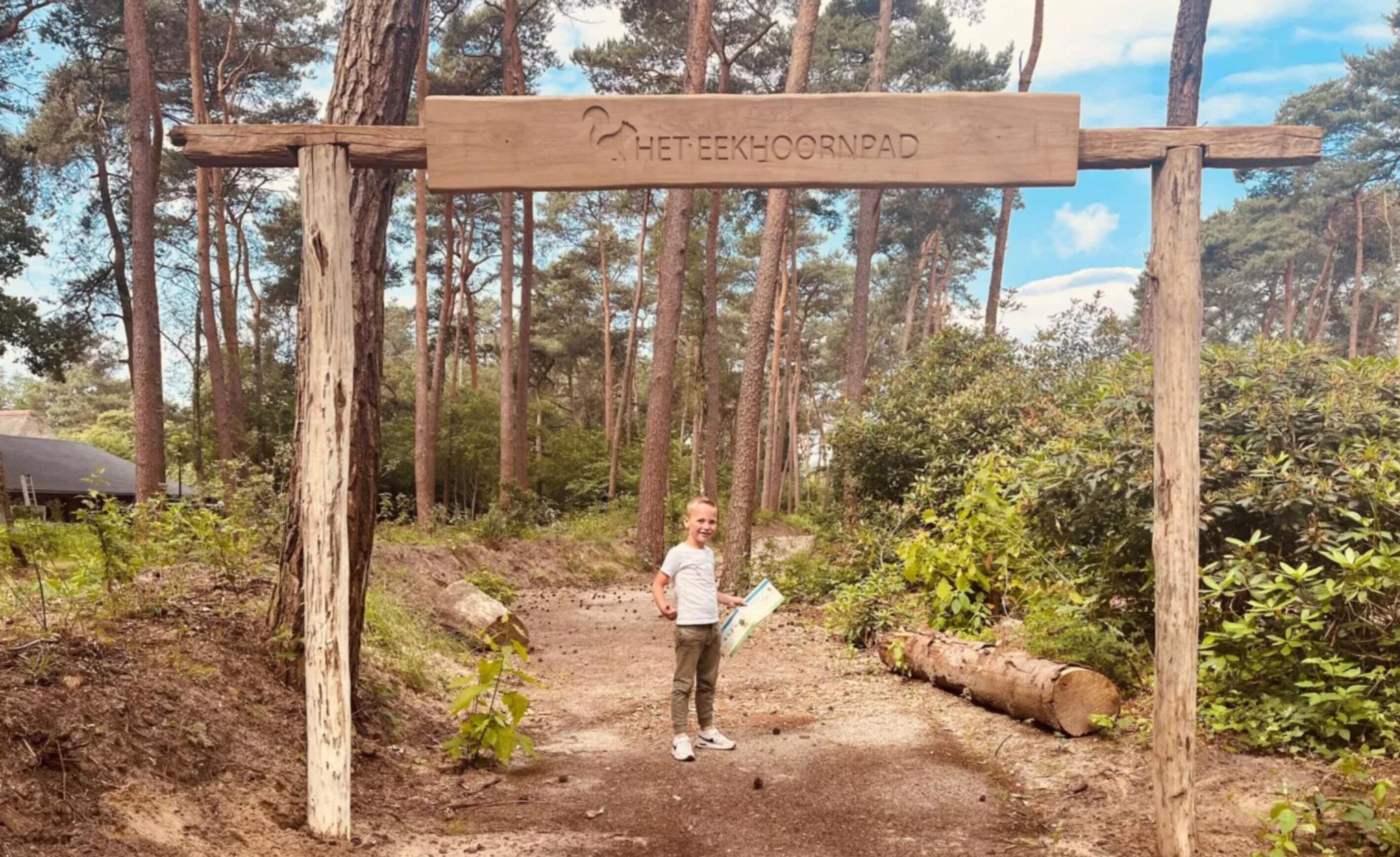 A wooden sign with the text 'HETTE EEKHOORNPAD' in a forested area.