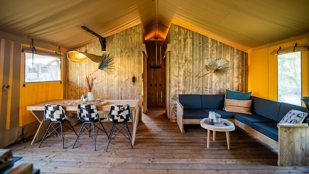 Un interior de madera con comedor, sofá y una pequeña mesa con sillas.