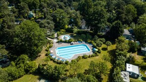 Vista aérea de un área residencial con piscina rodeada de árboles y casas.
