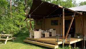 Terraza de madera con mobiliario exterior, una zona cubierta y una mesa de picnic.