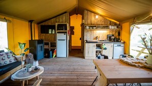 Un interior acogedor y rústico, con suelo de madera, una mesa de comedor, un sofá y una zona de cocina equipada con refrigerador, microondas y cafetera.