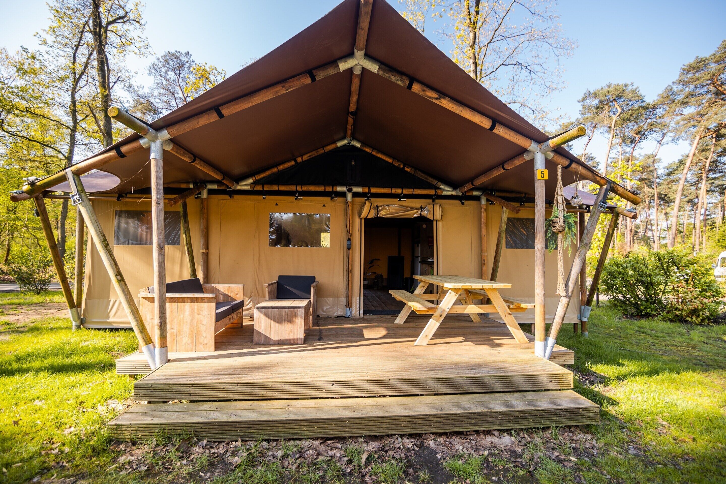 A wooden cabin with a covered porch, a picnic table, and a small seating area.