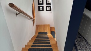 A staircase with wooden steps and black non-slip runners, white walls, and a blue accent wall.