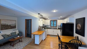A modern kitchen with white cabinets, a black refrigerator, and a wooden dining table.