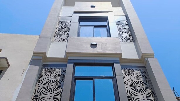 A building with a central window flanked by decorative panels and a smaller window above.