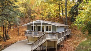 Eine Hütte mit einer Terrasse und Treppe, umgeben von Herbstlaub.