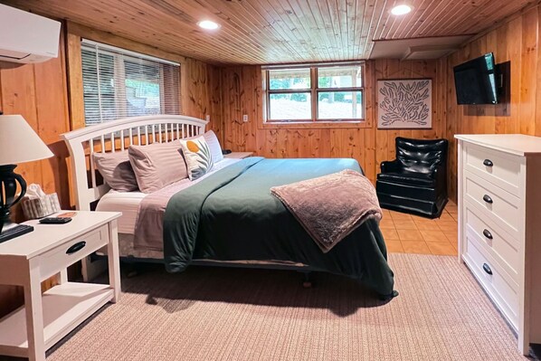 Un dormitorio con cama, mesita de noche, lámpara, cómoda y ventana con persianas.