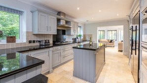 A modern kitchen with grey cabinets, black countertops, and a central island.