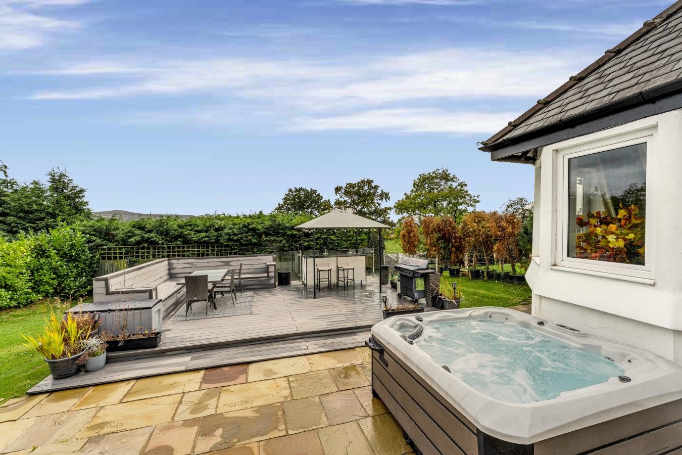 A patio area with a hot tub, outdoor furniture, and a pergola.