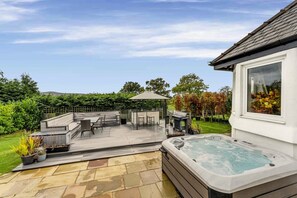 Un espace patio comprenant un jacuzzi, du mobilier d’extérieur et une pergola.
