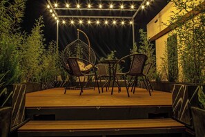 Relax on the outdoor patio, surrounded by lush greenery and comfortable wicker seating.