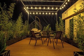 Relax in a serene outdoor space with a wooden deck surrounded by lush greenery, perfect for dining or socializing.