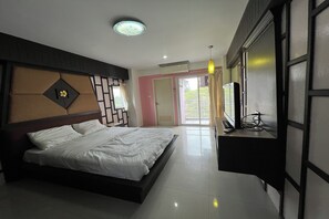 A modern hotel room with a bed, a desk, and a view of the outdoors. - Pongsatorn Mansion by Zuzu (Bangkok)