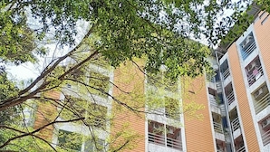 A multi-story building with a mix of brick and white exterior walls, air conditioning units on the windows, and a sign indicating a business or service on the ground floor. - Pongsatorn Mansion by Zuzu (Bangkok)