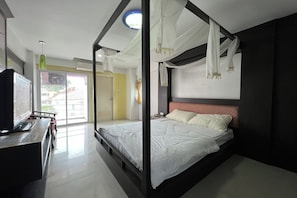 A modern bedroom with a bed, bedside table, and a view of the outside. - Pongsatorn Mansion by Zuzu (Bangkok)