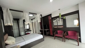 A bedroom with a bed, a desk, a chair, a wardrobe, and a mirror. - Pongsatorn Mansion by Zuzu (Bangkok)