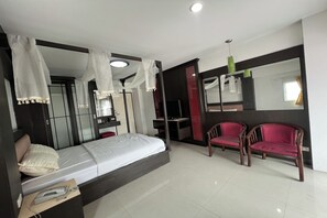 A bedroom with a bed, a desk, a chair, a wardrobe, and a mirror. - Pongsatorn Mansion by Zuzu (Bangkok)