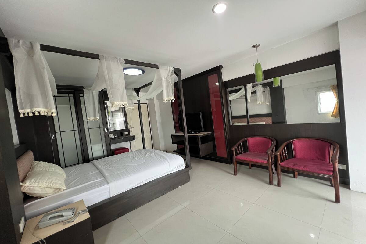 A bedroom with a bed, a desk, a chair, a wardrobe, and a mirror.