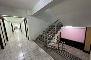 A hallway with a staircase leading to a pink wall. - Pongsatorn Mansion by Zuzu (Bangkok)