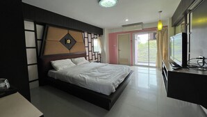 A modern bedroom with a bed, bedside table, and a TV on a stand. - Pongsatorn Mansion by Zuzu (Bangkok)