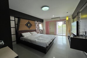 A modern bedroom with a bed, bedside table, and a TV on a stand. - Pongsatorn Mansion by Zuzu (Bangkok)