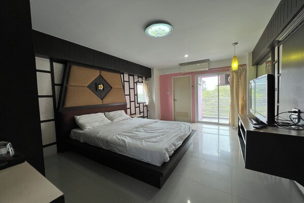 A modern bedroom with a bed, bedside table, and a TV on a stand. - Pongsatorn Mansion by Zuzu (Bangkok)