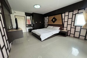 A bedroom with a bed, bedside tables, a dresser, and a mirror. - Pongsatorn Mansion by Zuzu (Bangkok)